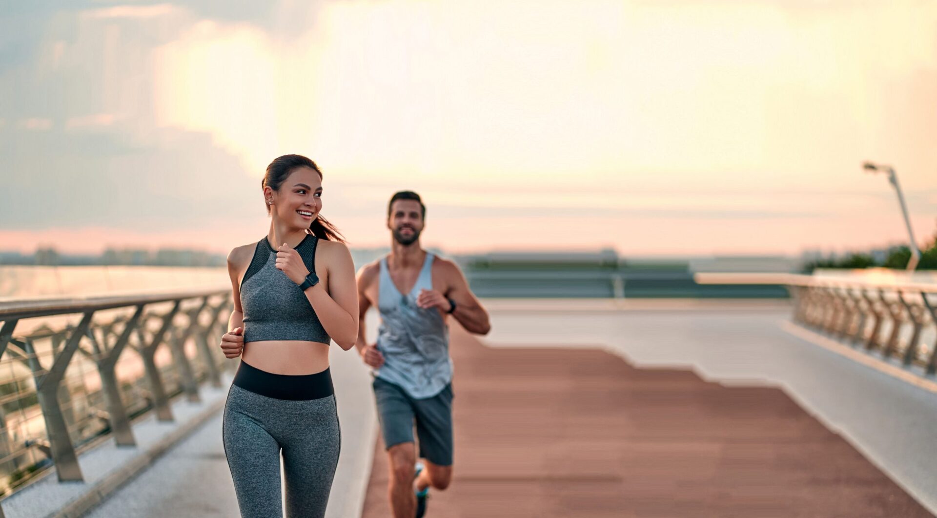Fit, attractive couple running on a pier with the sun setting behind them to model Wellnessesity treatment benefits for the gravity form section of the Semaglutide page.